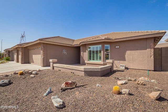 view of front facade featuring driveway, an attached garage, a tile roof, and stucco siding