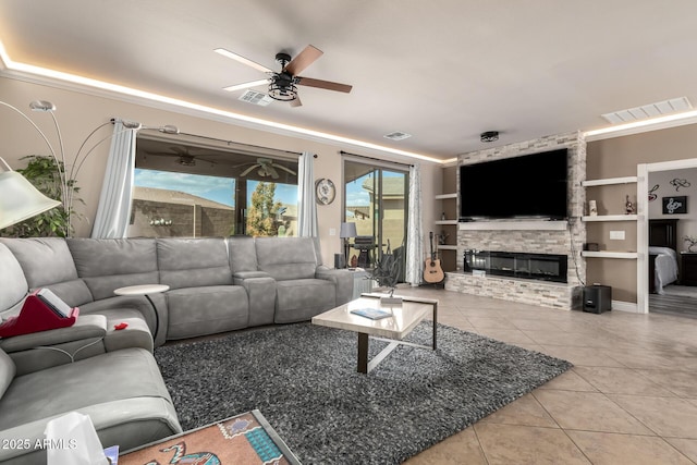 tiled living area featuring built in shelves, visible vents, a fireplace, and ceiling fan