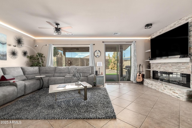 tiled living area with a large fireplace, ornamental molding, and a ceiling fan