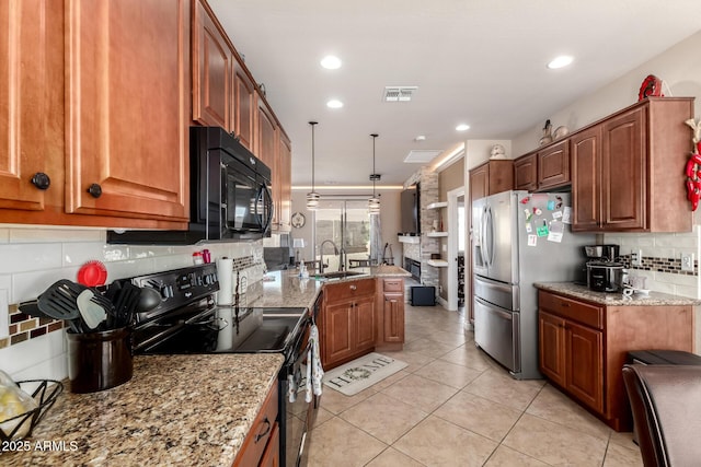 kitchen with visible vents, brown cabinetry, a sink, a peninsula, and black appliances