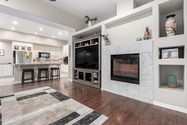 living room featuring sink, a fireplace, built in features, and dark hardwood / wood-style floors