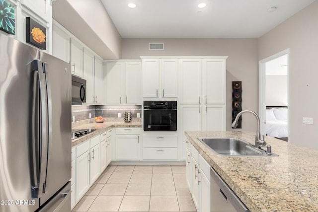 kitchen with sink, black appliances, light tile patterned floors, white cabinets, and backsplash