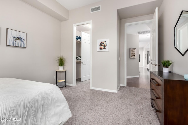 bedroom with a closet, a spacious closet, and light carpet