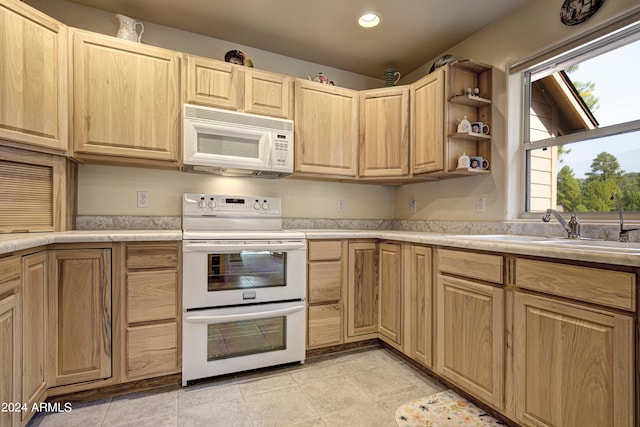 kitchen with lofted ceiling, white appliances, sink, light brown cabinetry, and light tile patterned flooring