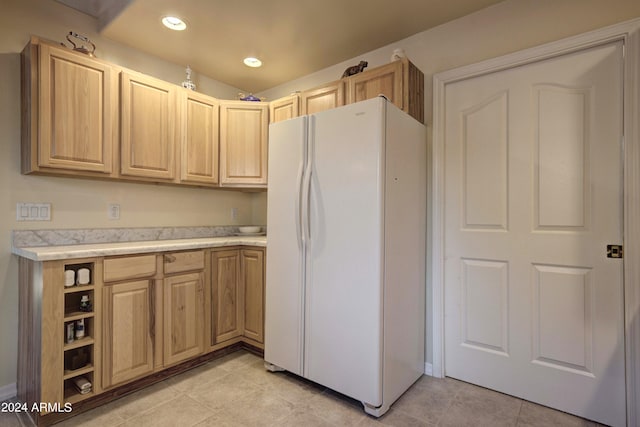 kitchen featuring white refrigerator, light tile patterned flooring, and light brown cabinets