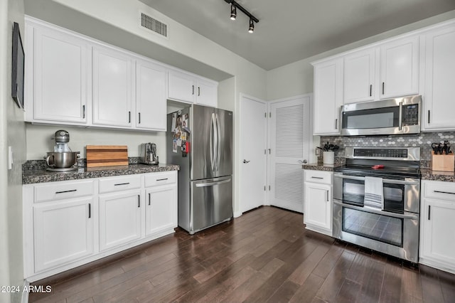 kitchen featuring tasteful backsplash, dark hardwood / wood-style floors, dark stone countertops, white cabinets, and appliances with stainless steel finishes