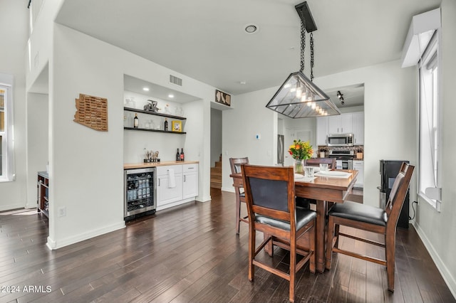 dining area with dark wood-type flooring, beverage cooler, and indoor bar