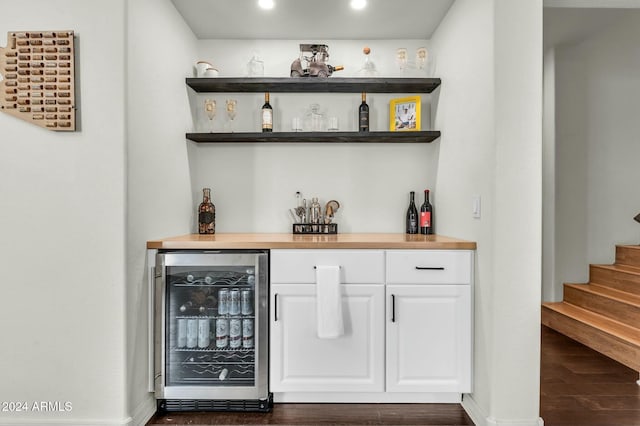 bar featuring wood counters, dark hardwood / wood-style floors, white cabinetry, and beverage cooler