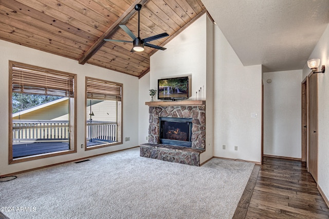 unfurnished living room with a stone fireplace, wooden ceiling, beam ceiling, ceiling fan, and dark hardwood / wood-style floors