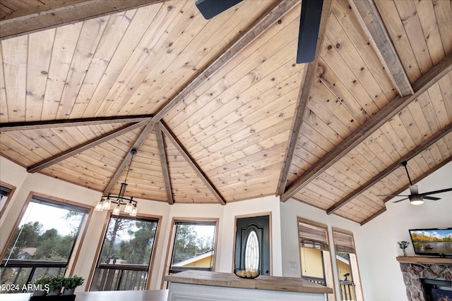 room details featuring wooden ceiling, ceiling fan with notable chandelier, a stone fireplace, and beamed ceiling