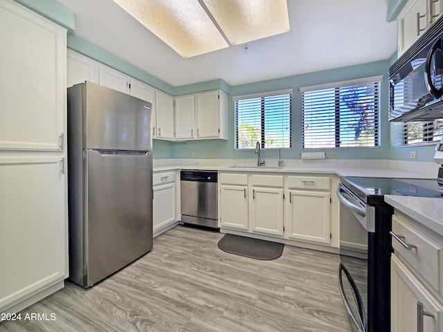 kitchen with light wood-type flooring, white cabinets, stainless steel appliances, and a sink