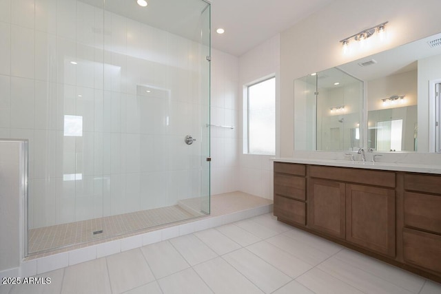 bathroom with tile patterned flooring, vanity, and a tile shower