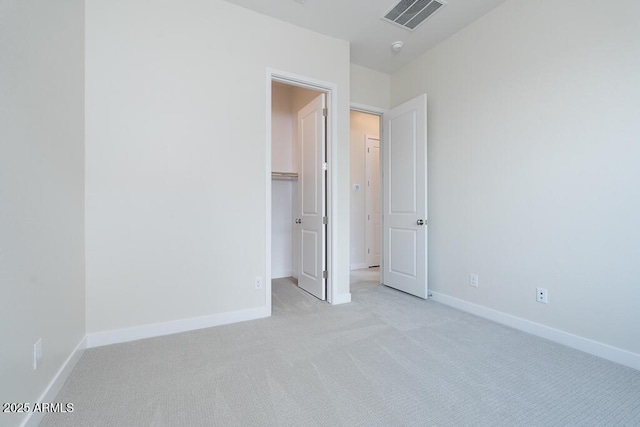 unfurnished bedroom featuring light carpet and a walk in closet