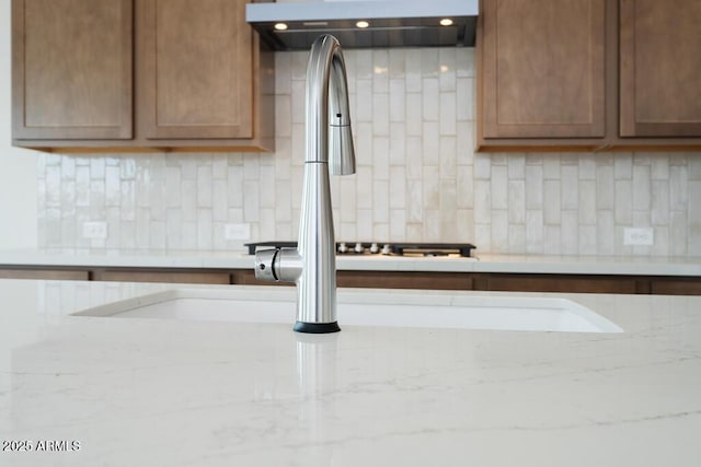 interior details with light stone counters, tasteful backsplash, and range hood