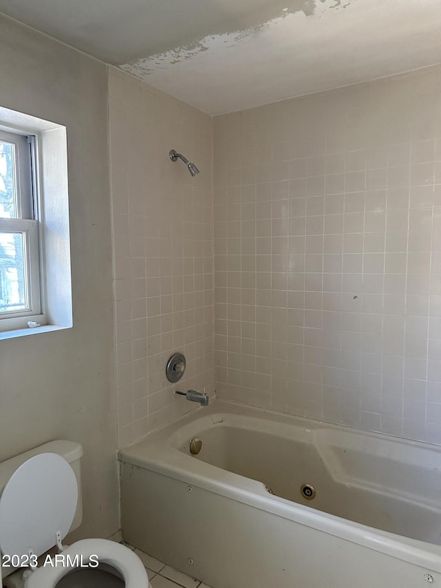 bathroom with tiled shower / bath combo, toilet, and tile floors