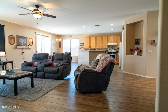 living room with ceiling fan with notable chandelier and light hardwood / wood-style floors