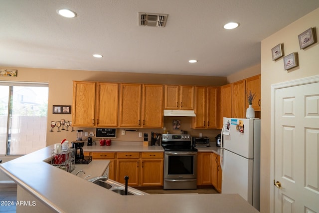 kitchen featuring stainless steel electric stove, white refrigerator, kitchen peninsula, and sink