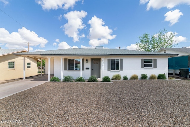 ranch-style home with driveway, an attached carport, and a shingled roof