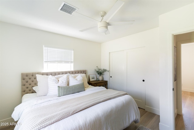 bedroom with a closet, wood finished floors, ceiling fan, and baseboards