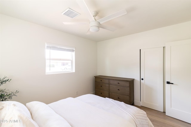 bedroom with light wood-style floors, ceiling fan, and a closet