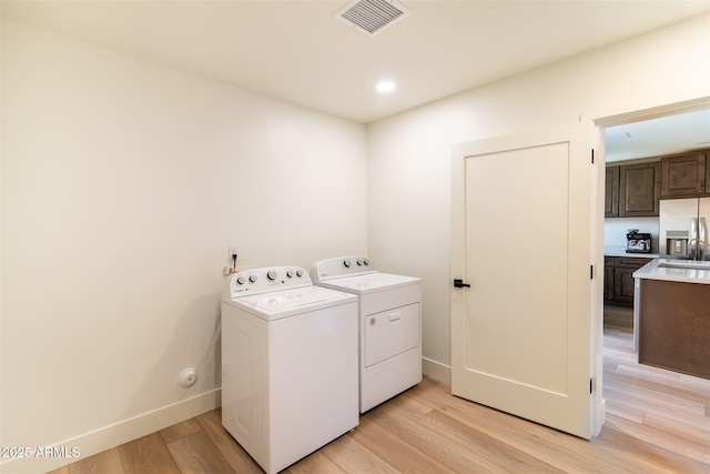 washroom with washer and dryer, light wood-style flooring, baseboards, and recessed lighting