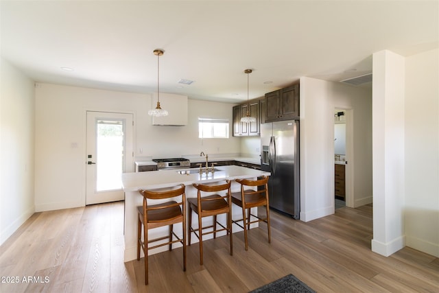 kitchen with appliances with stainless steel finishes, a sink, light countertops, and light wood-style flooring