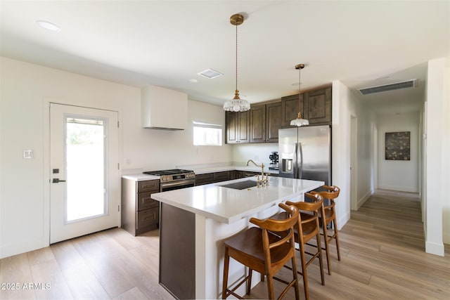 kitchen with a sink, appliances with stainless steel finishes, light countertops, light wood finished floors, and recessed lighting