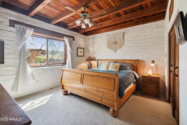 carpeted bedroom with beamed ceiling, a ceiling fan, wooden ceiling, and brick wall