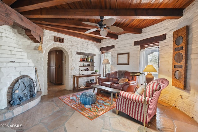 living area featuring stone tile floors, visible vents, arched walkways, ceiling fan, and wooden ceiling