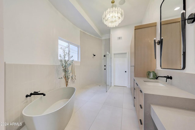 bathroom featuring tile walls, vanity, a bath, a notable chandelier, and tile patterned floors