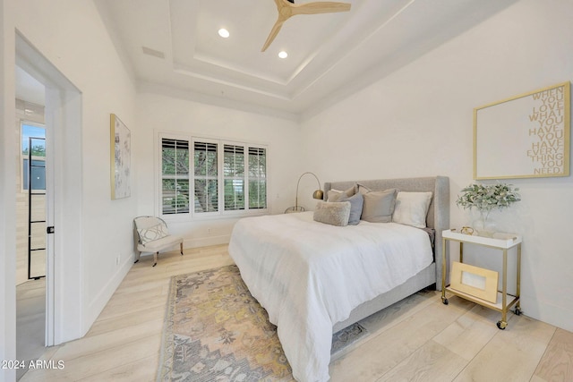 bedroom featuring wood-type flooring, a tray ceiling, and multiple windows