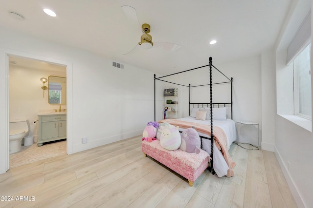 bedroom featuring multiple windows, light hardwood / wood-style flooring, ceiling fan, and ensuite bathroom