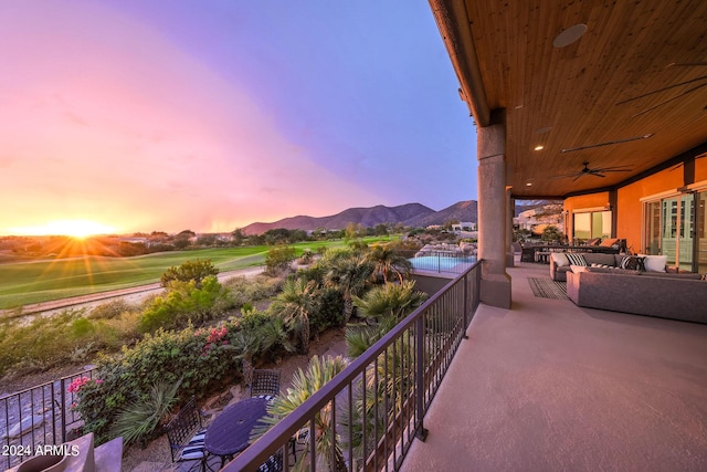 balcony at dusk featuring a mountain view and ceiling fan