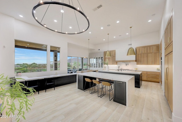 kitchen with pendant lighting, a breakfast bar, and a large island with sink