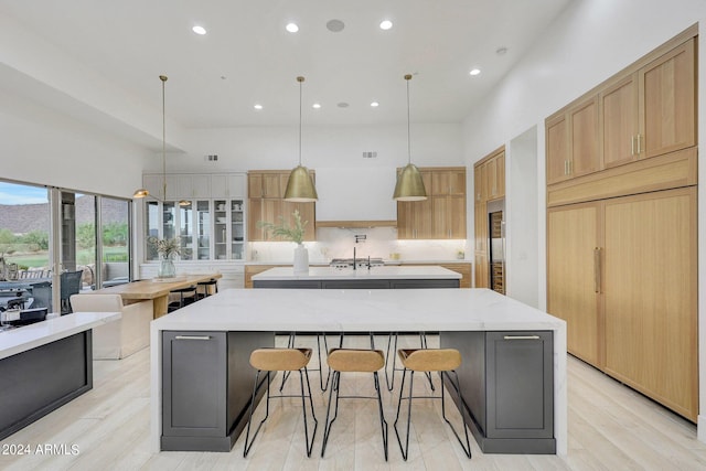 kitchen featuring light stone countertops, a high ceiling, hanging light fixtures, and a large island with sink