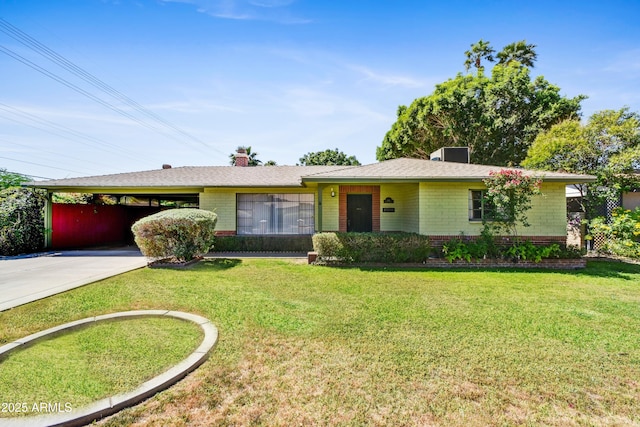 single story home with a chimney, brick siding, an attached carport, a front lawn, and concrete driveway