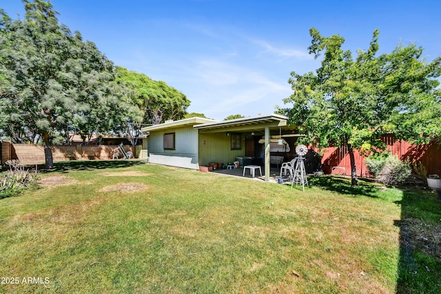 rear view of property featuring a patio area, a yard, and a fenced backyard