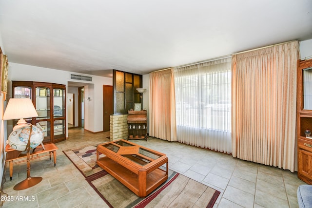 living area featuring tile patterned flooring, visible vents, and plenty of natural light