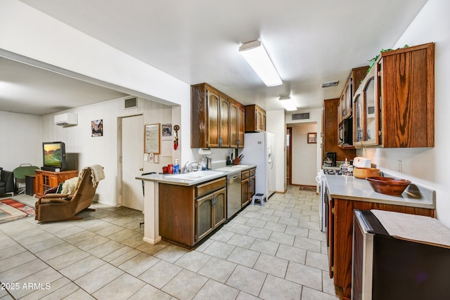 kitchen featuring a sink, visible vents, light countertops, an AC wall unit, and white appliances