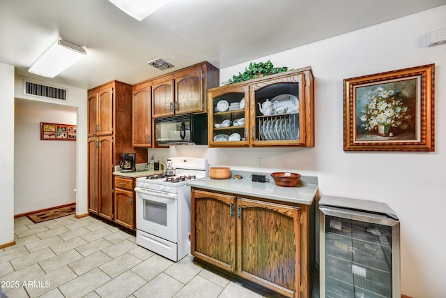 kitchen with wine cooler, gas range gas stove, black microwave, visible vents, and light countertops