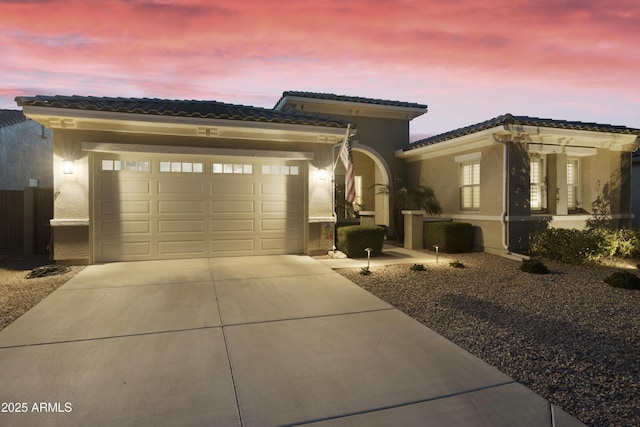 view of front of home with an attached garage, a tile roof, concrete driveway, and stucco siding