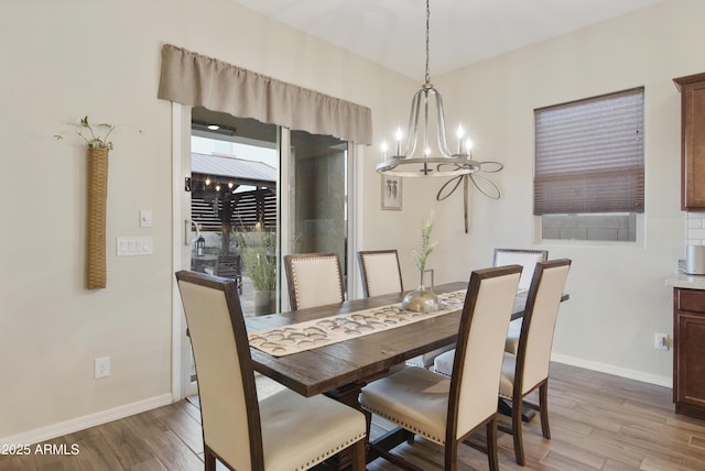 dining area featuring light wood-style flooring, baseboards, and a chandelier