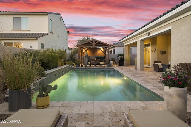 pool at dusk with a patio area, a fenced backyard, a fenced in pool, and a gazebo