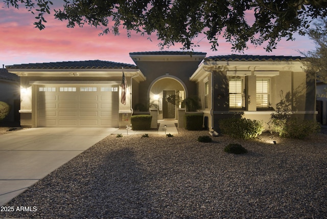 view of front of house with french doors, stucco siding, concrete driveway, an attached garage, and a tiled roof