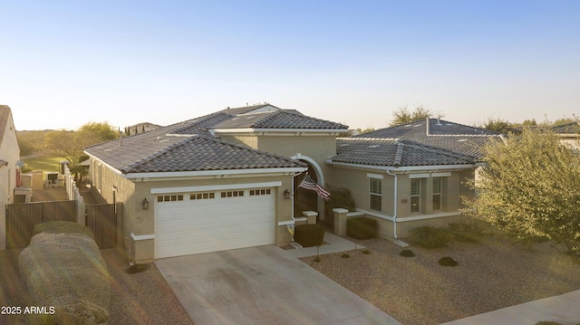 view of front facade featuring a garage, fence, a tile roof, driveway, and stucco siding