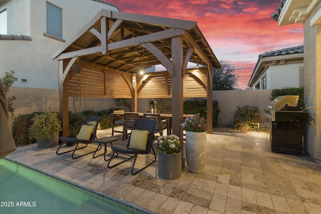 patio terrace at dusk with outdoor dining space, a fenced backyard, and a gazebo