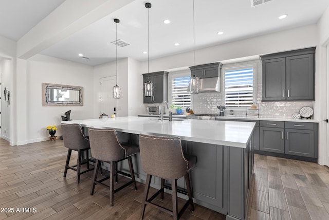 17385 W Sugar Hill Ct, Surprise, AZ 85388 - kitchen with a sink, gray cabinets, tasteful backsplash, a kitchen bar, and wood finished floors