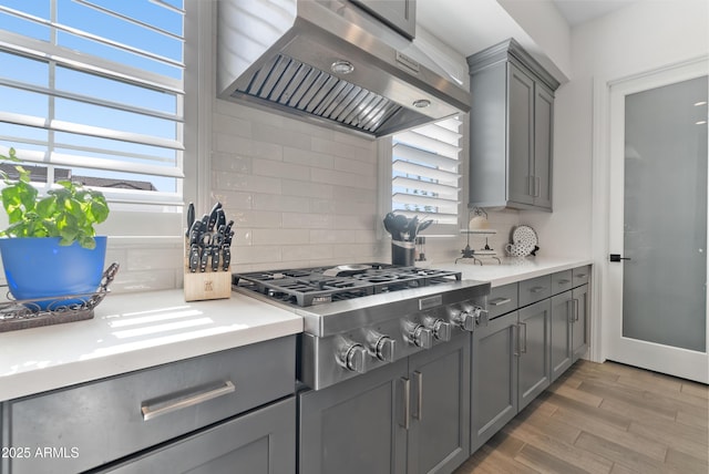 17385 W Sugar Hill Ct, Surprise, AZ 85388 - kitchen with gray cabinetry, extractor fan, stainless steel gas stovetop, and decorative backsplash
