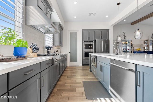 17385 W Sugar Hill Ct, Surprise, AZ 85388 - kitchen with stainless steel appliances, gray cabinetry, ventilation hood, backsplash, and recessed lighting