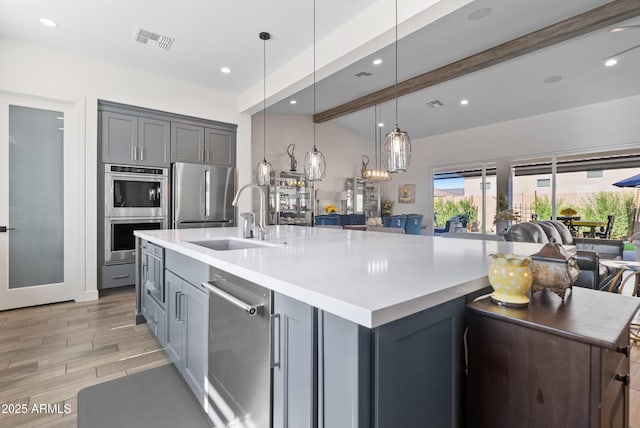 17385 W Sugar Hill Ct, Surprise, AZ 85388 - kitchen with gray cabinetry, a sink, stainless steel appliances, a spacious island, and beamed ceiling